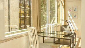 Een moderne eetruimte met een glazen tafel, witte stoelen en grote ramen met uitzicht op de stad.