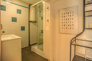 A bathroom with a shower, a sink, and a glass door.