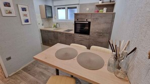 Une cuisine moderne avec un coin repas, comprenant une table en bois, des chaises et un four encastré.