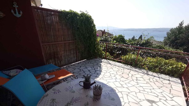 Une terrasse avec une table ronde, des chaises et une vue sur la mer.