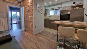 Une cuisine moderne avec coin repas, agrémentée d’un mur d’accent en pierre, de planchers en bois et d’appareils électroménagers contemporains.