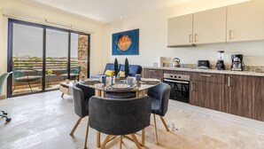 A modern kitchen with a dining area, large windows, and a city view. - Veranto (Playa del Carmen)