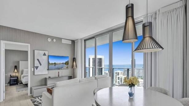 A modern hotel room with a balcony, a dining area, and a living space. - Enjoy the perfect blend of comfort, elegance, and luxury in this stunning 3-bedroom apartment (Hollywood)