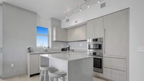A modern kitchen with a central island, stainless steel appliances, and a large window. - Enjoy the perfect blend of comfort, elegance, and luxury in this stunning 3-bedroom apartment (Hollywood)