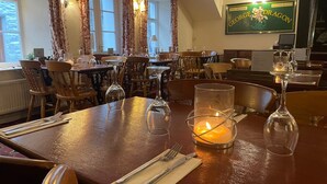 A restaurant interior with wooden tables, chairs, and a candle centerpiece. - George and Dragon Dent (Sedbergh)
