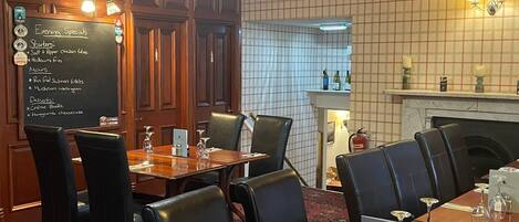 A restaurant with a blackboard menu, wooden paneling, and a fireplace.