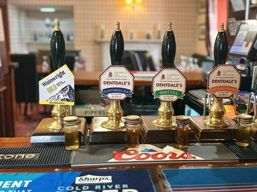 A bar with multiple taps, including brands like George and Dragon, Dentdale's, and Wyomissing Gold.