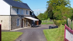 A stone building with a covered porch and a paved driveway leading to a gate.
