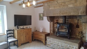 A cozy room with a stone fireplace, a wooden cabinet, a television, and a chair.