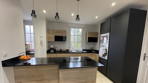 A modern kitchen with a central island, black countertops, wooden cabinetry, and a built-in oven. - 2 bedrooms, 2 bathrooms appartement with terrace and balcony, close to beaches (Arcachon)