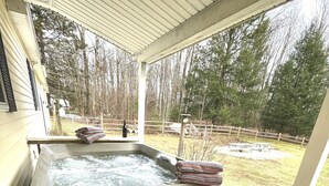 A hot tub on a wooden deck with a view of a fenced yard and trees.