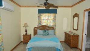 A bedroom with a bed, a nightstand, a dresser, a ceiling fan, and a mirror. - Cassaruina Studio 3 (Rolleville)