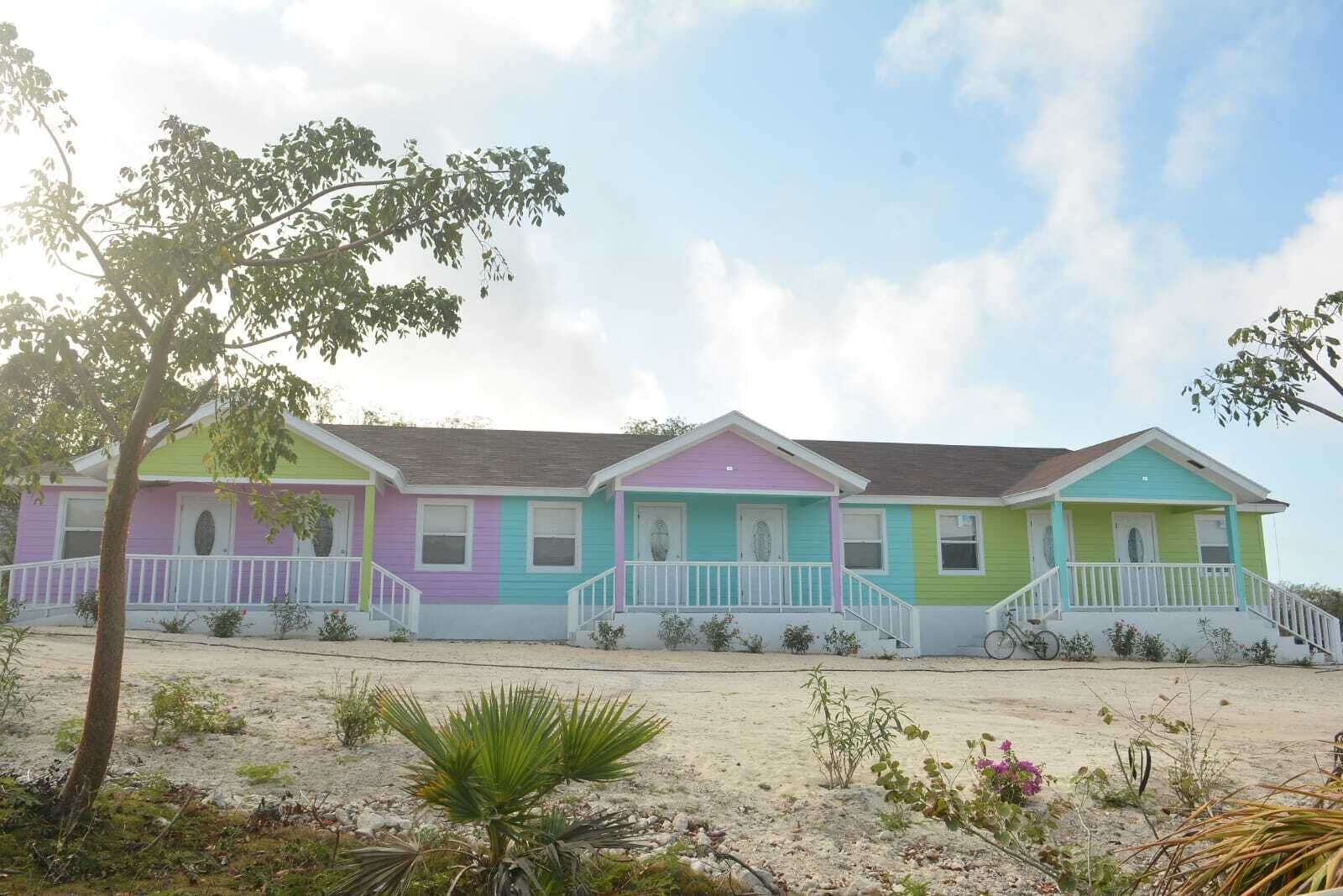 A row of colorful beach houses with a sandy foreground and a clear sky.