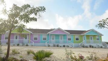 A row of colorful beach houses with a sandy foreground and a clear sky.