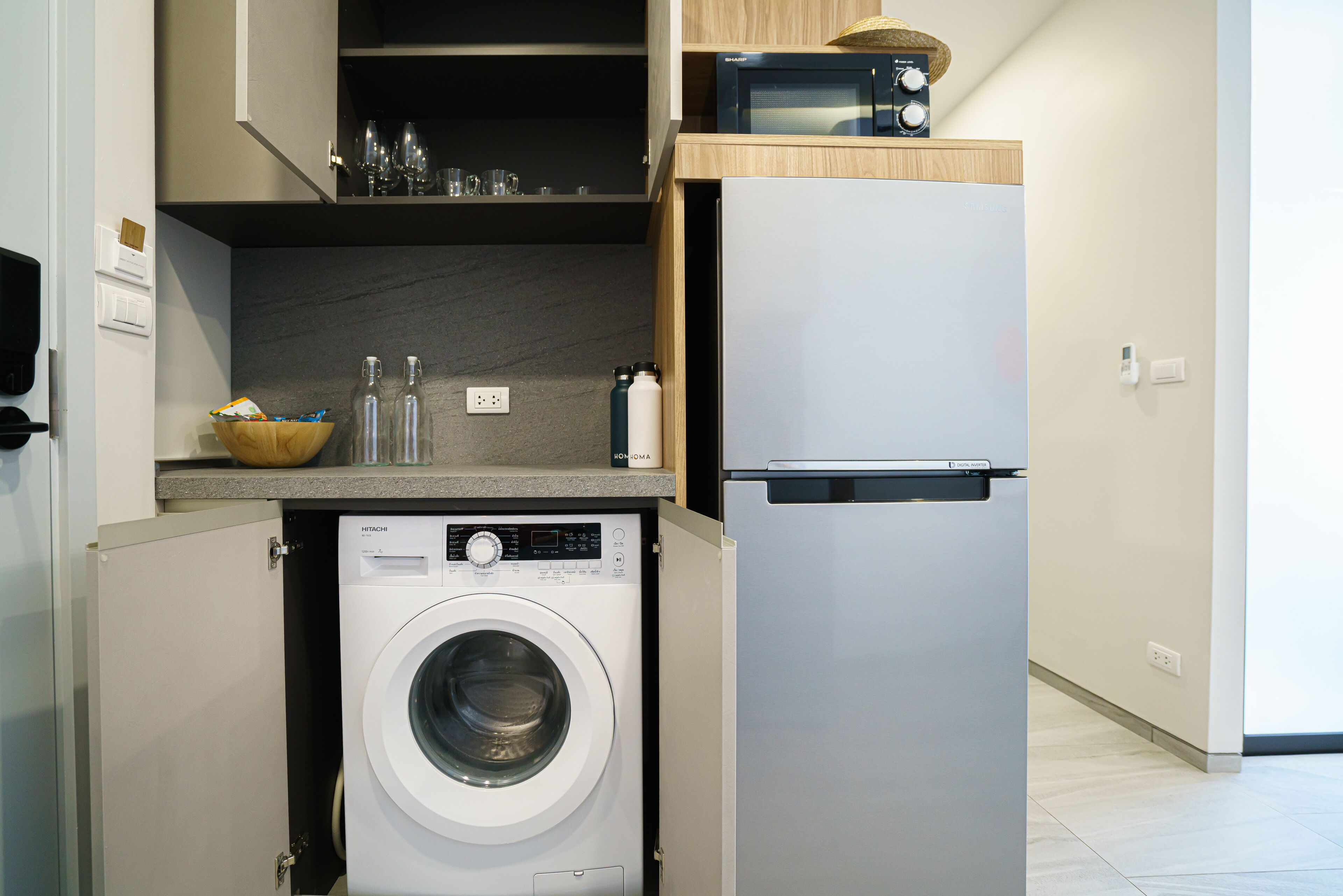 Eine kompakte Küche mit integrierter Waschmaschine und Trockner, einer Mikrowelle und einem Kühlschrank.
