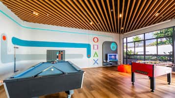 Un área recreativa interior moderna con mesa de billar, mesa de futbolín y televisor.