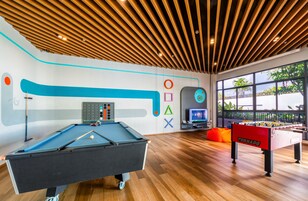 Un área recreativa interior moderna con mesa de billar, mesa de futbolín y televisor.