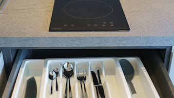 Une cuisine dotée d’une plaque de cuisson à induction noire et d’un tiroir contenant des ustensiles de cuisine.