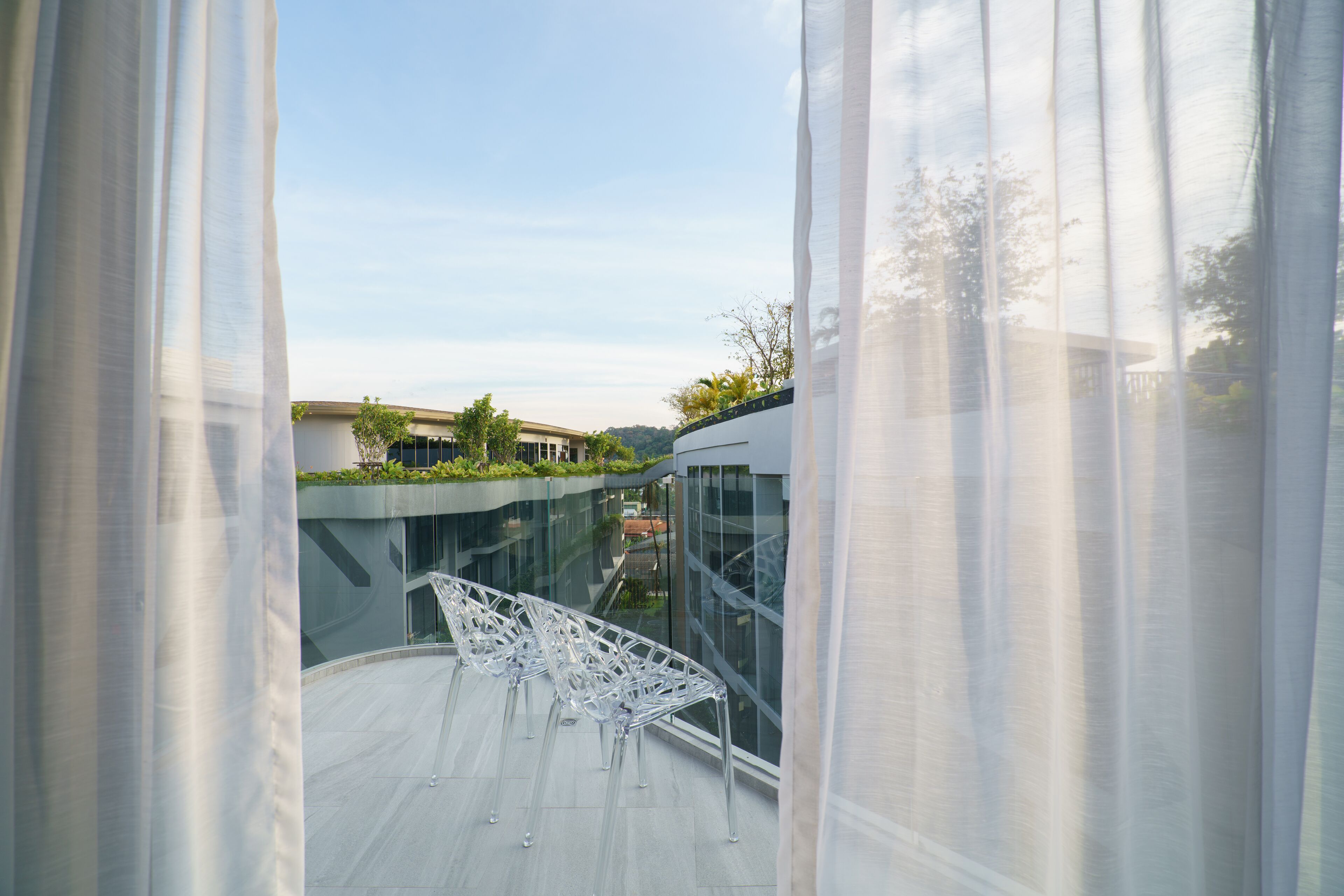 A modern building with glass walls and a rooftop garden.
