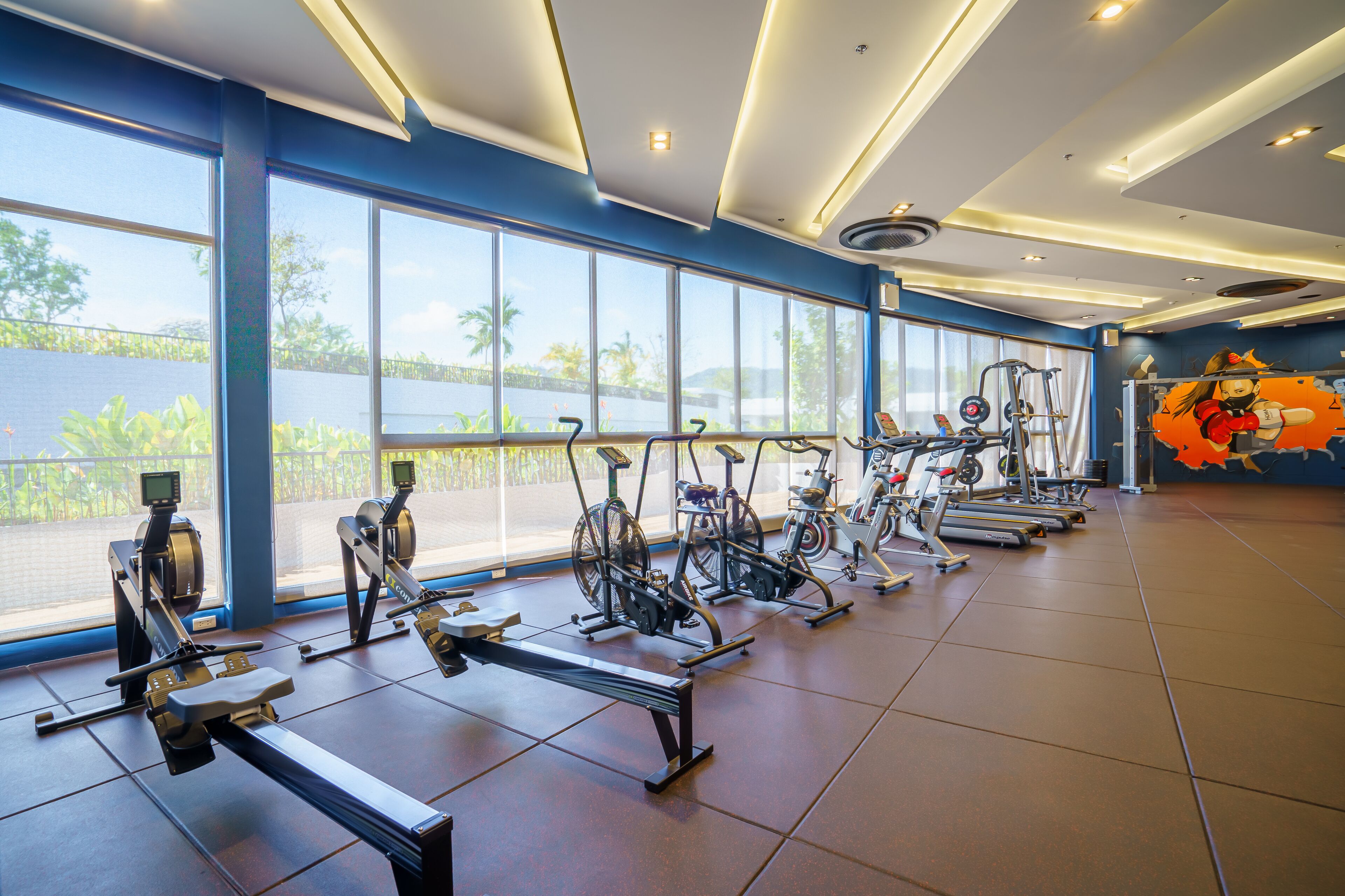 A gym with exercise equipment, large windows, and a view of the outdoors.