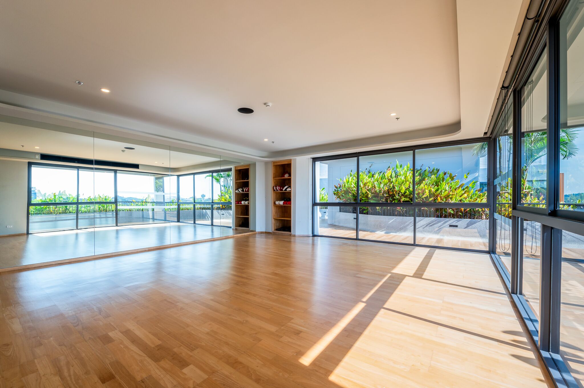 A spacious room with large windows, wooden flooring, and built-in shelving.