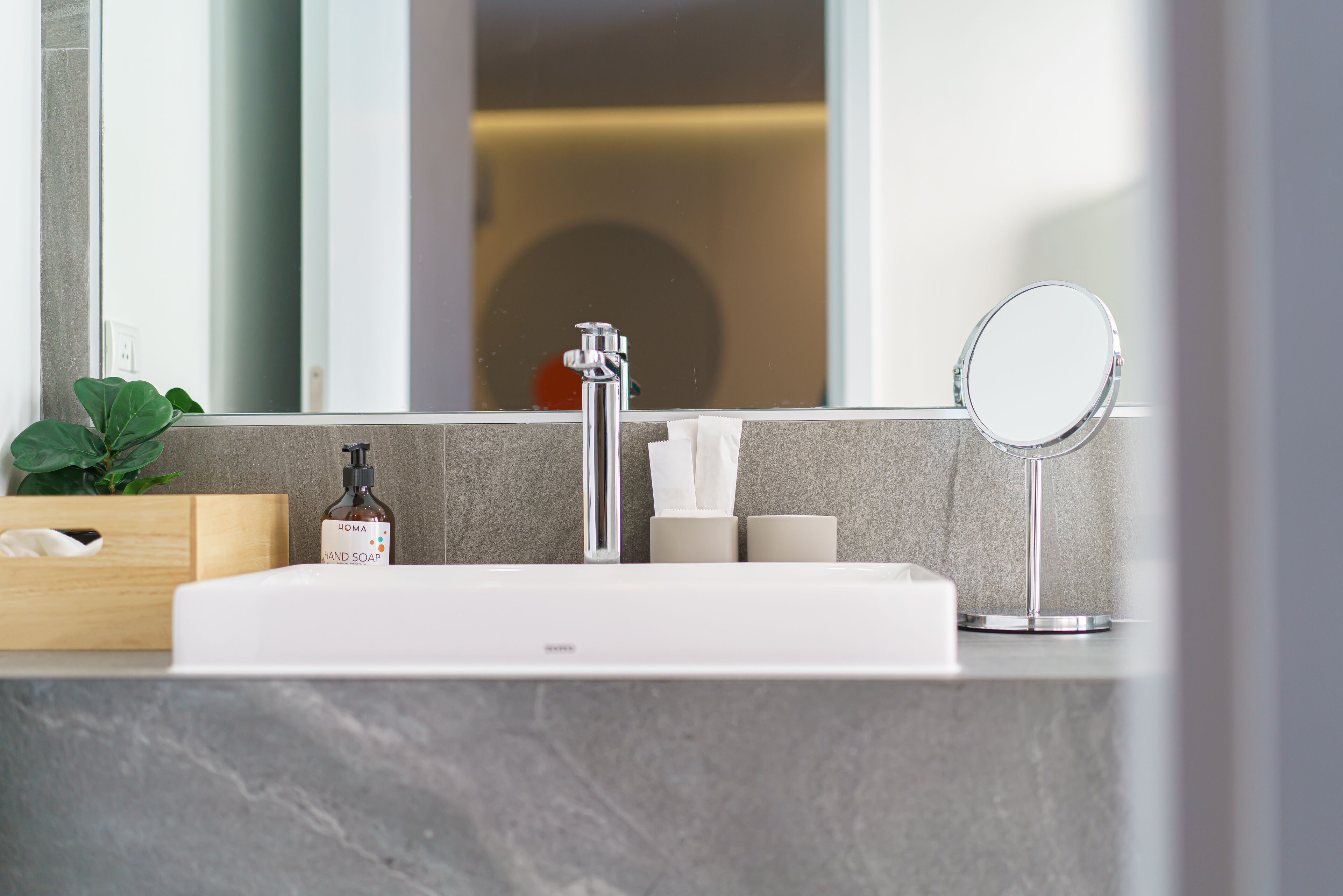 Un baño con un lavamanos blanco, un espejo y una planta.