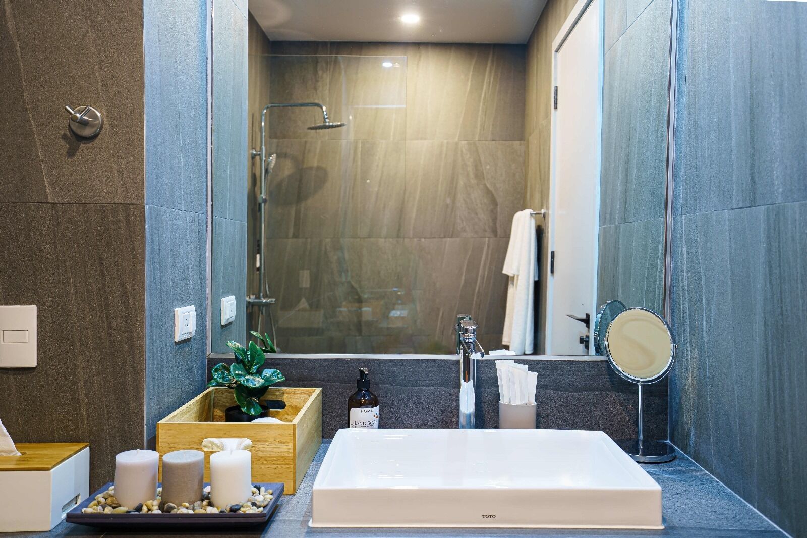 Un bagno moderno con una vasca da bagno spaziosa, uno specchio e un lavandino. Sul ripiano ci sono candele e una pianta.