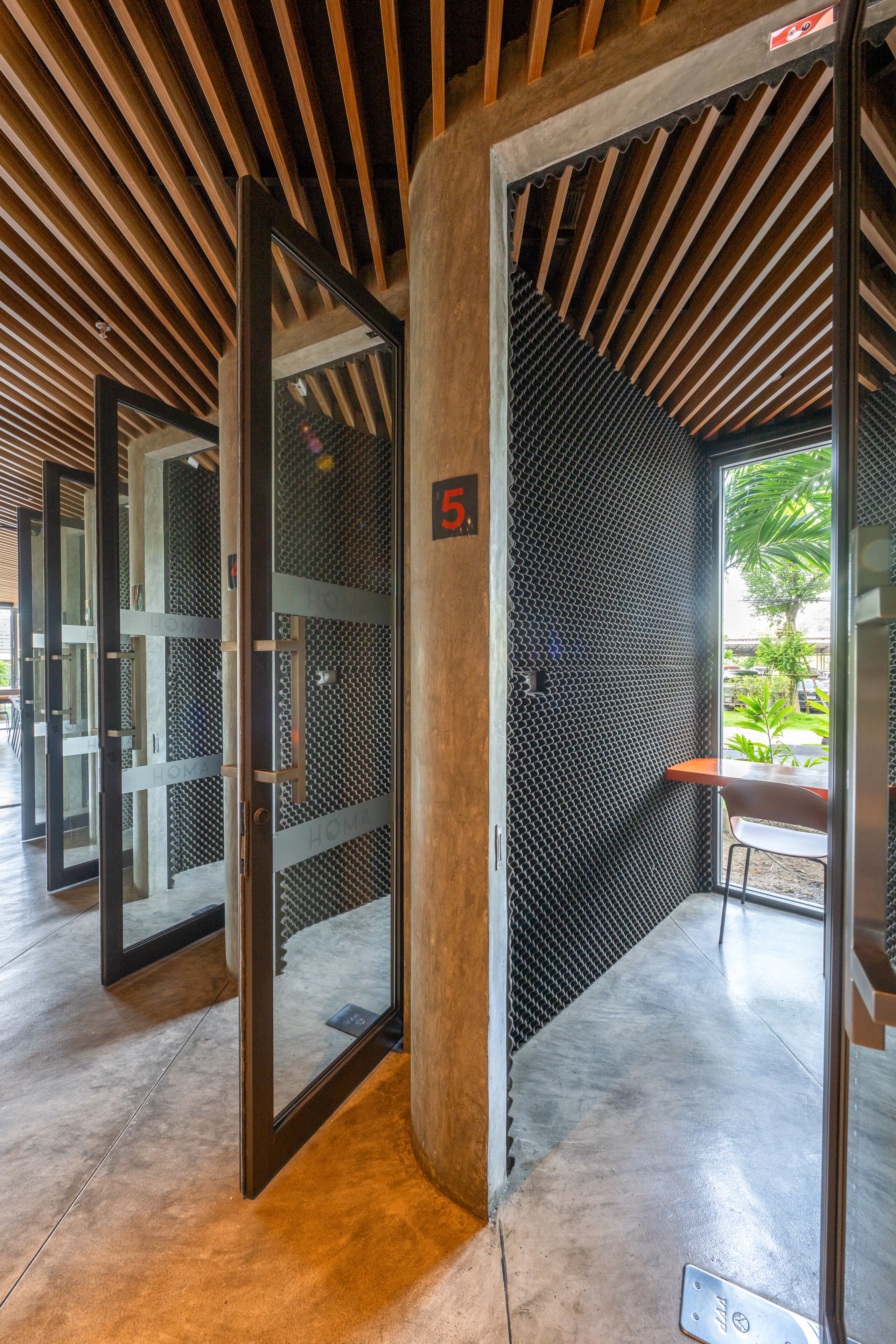 Un interior moderno con techo de madera, puertas de cristal y suelo de hormigón.