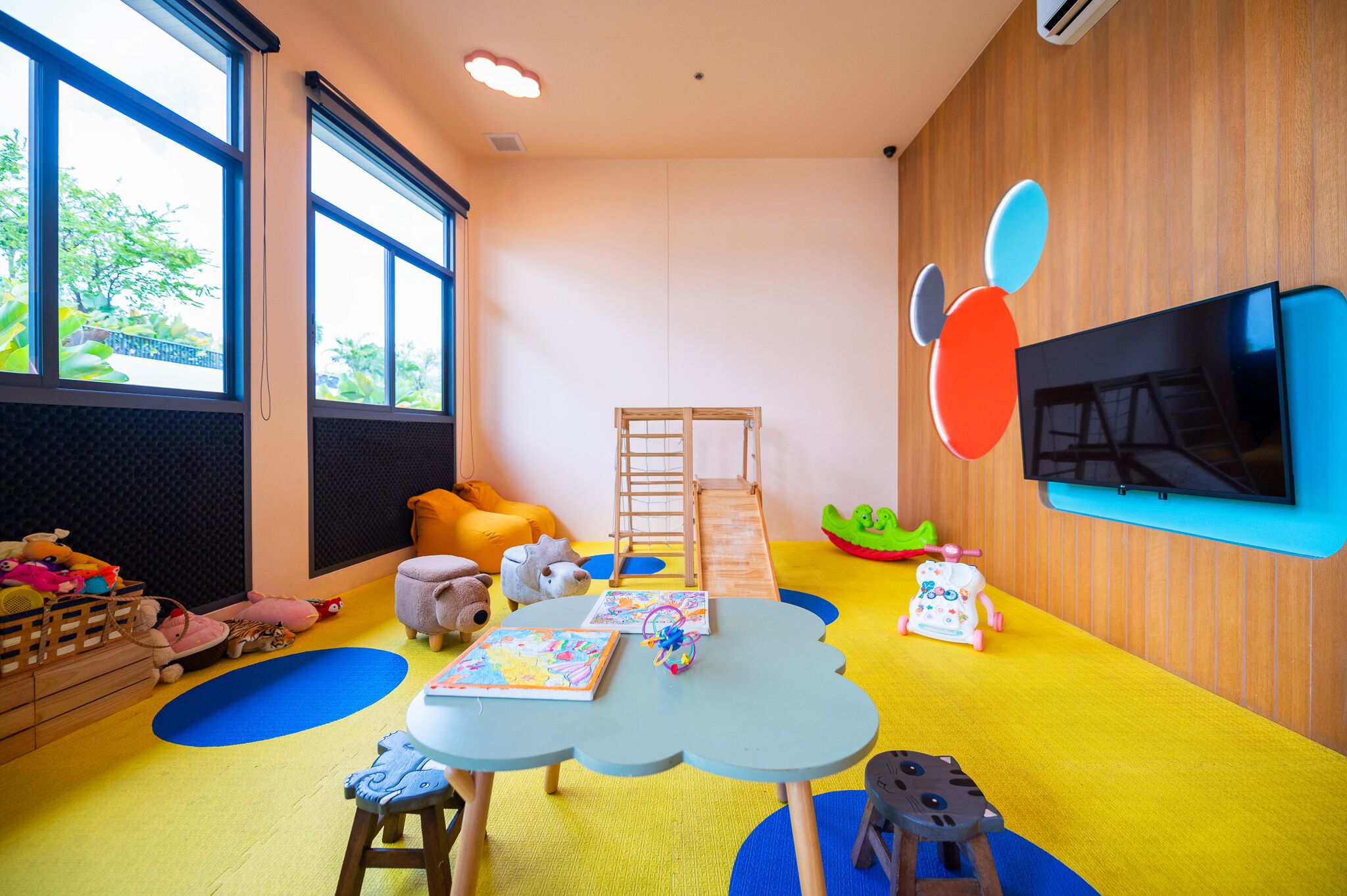 A child-friendly room with a play area, large windows, and a TV.