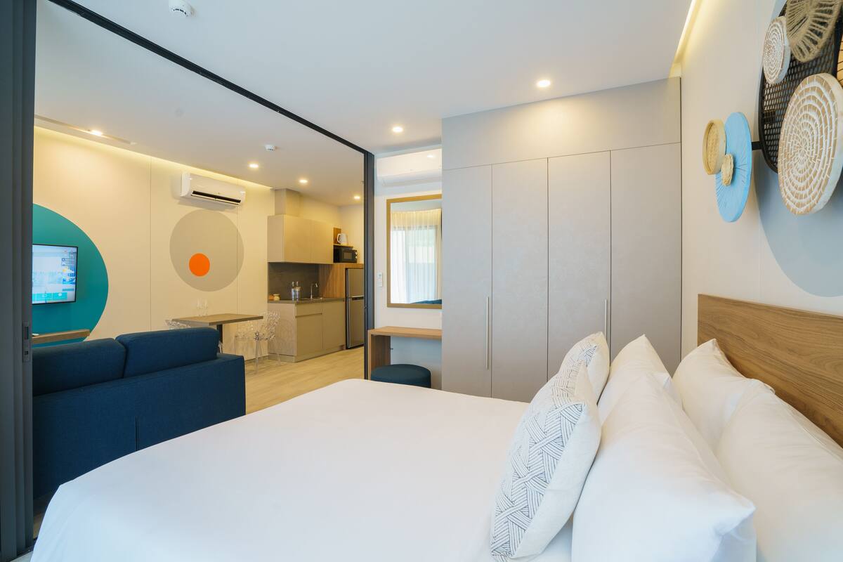Una habitación de hotel moderna con una cama grande, un sofá, una kitchenette y un baño.
