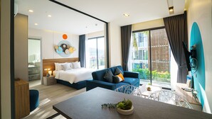 A modern hotel room with a bed, sofa, dining table, and a view of the outdoors. - HOMA Phuket Town (Ratsada)