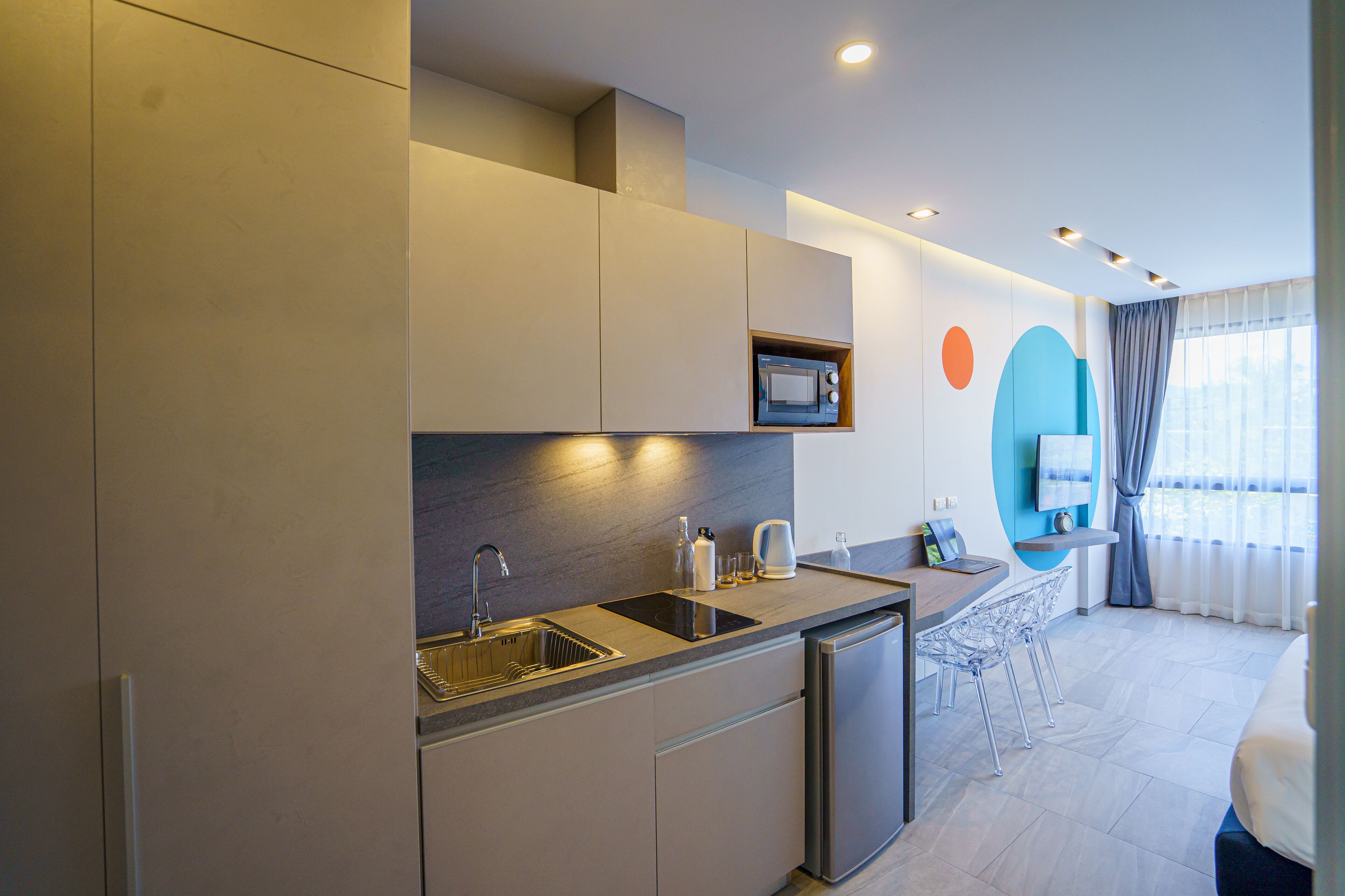 A modern kitchen with a built-in microwave, stainless steel sink, and a compact dishwasher.
