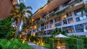A multi-story hotel with balconies, lush greenery, and outdoor lighting. - HOMA Phuket Town (Ratsada)