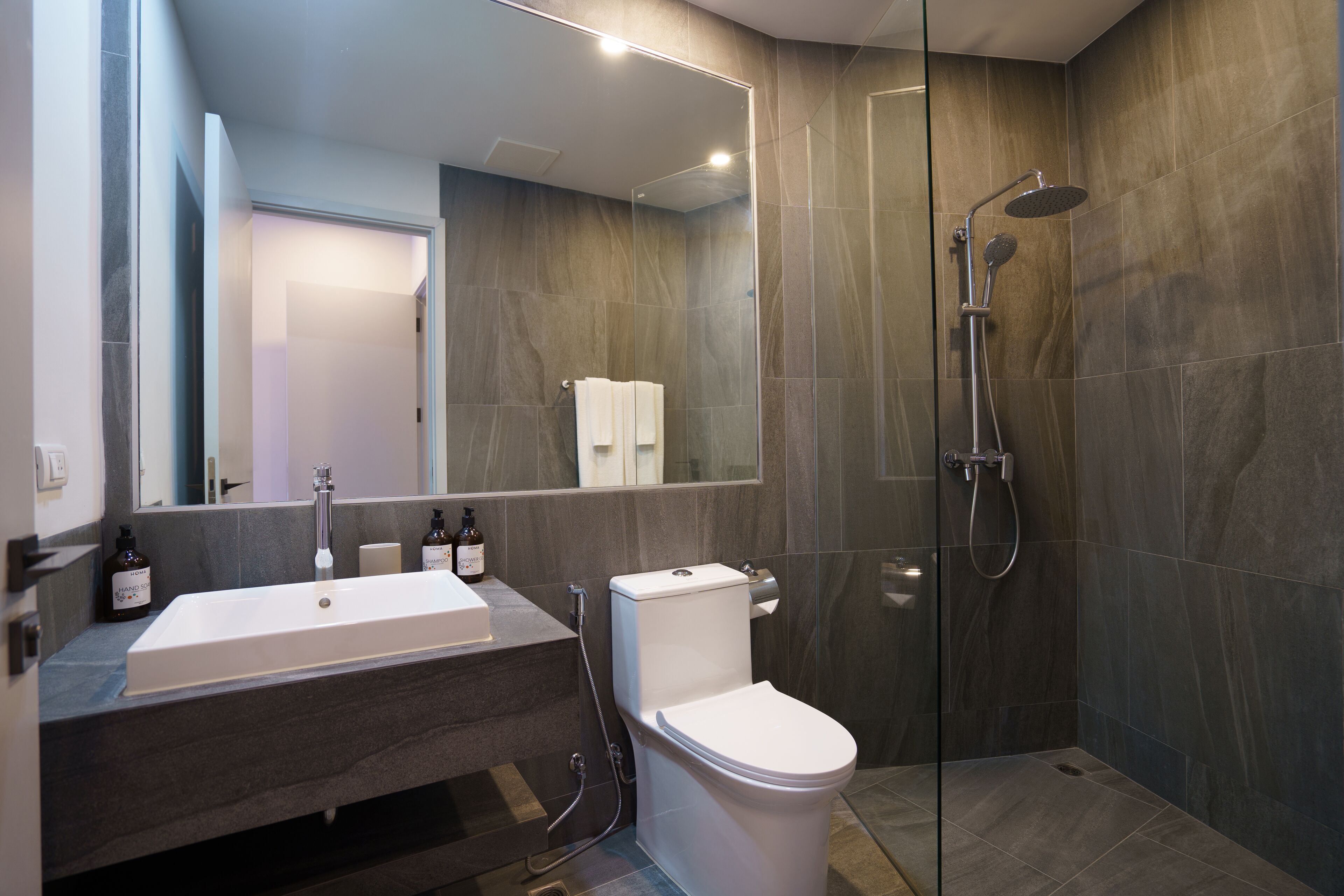Une salle de bain moderne avec un lavabo blanc, des toilettes et un espace douche.