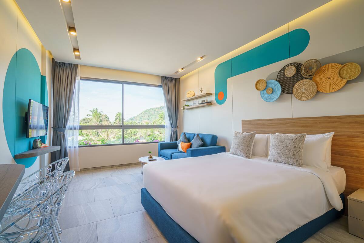 Una habitación de hotel moderna con una cama grande, un sofá, un televisor y un comedor.