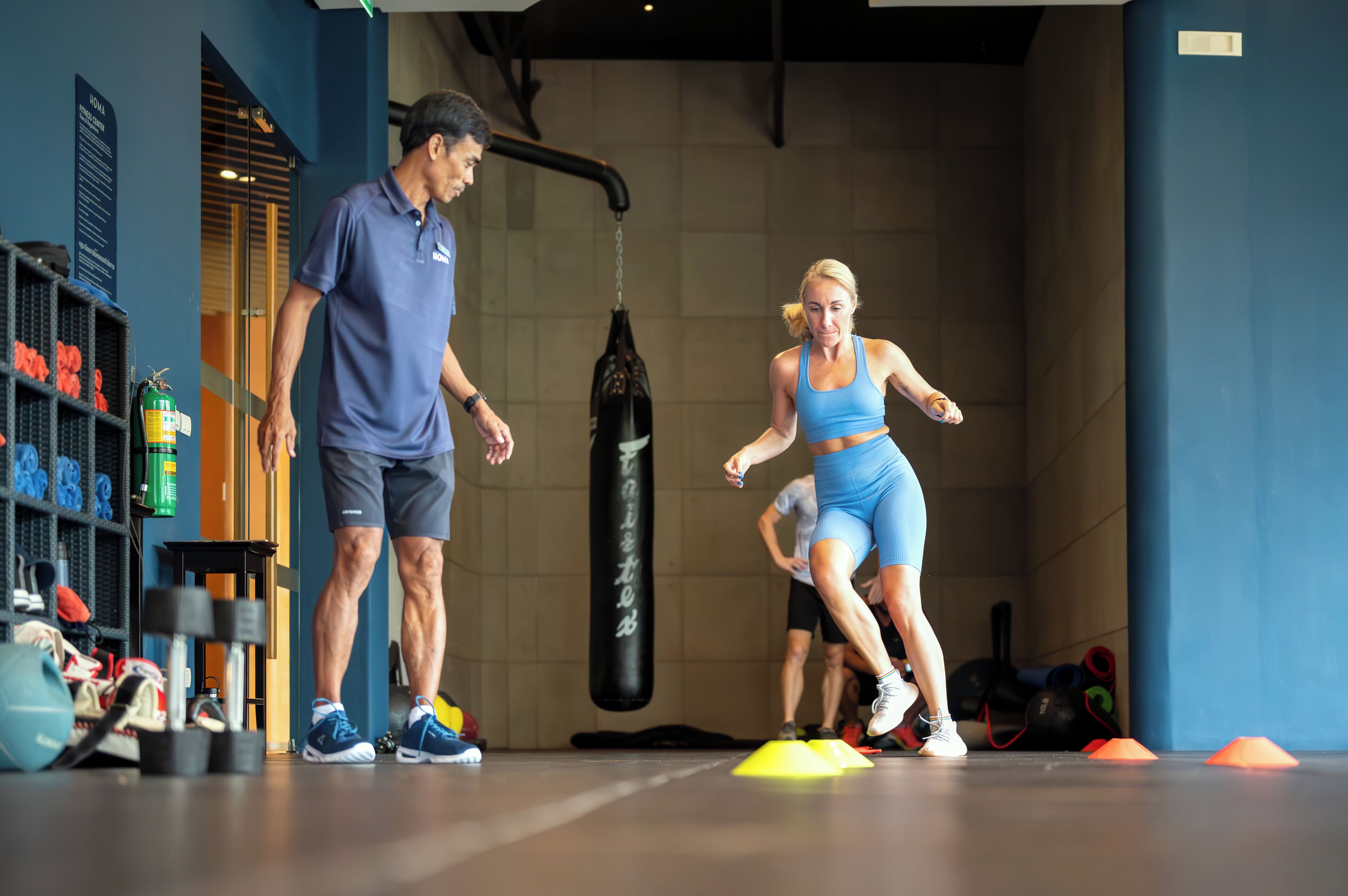 A gym with exercise equipment, a punching bag, and a person training.