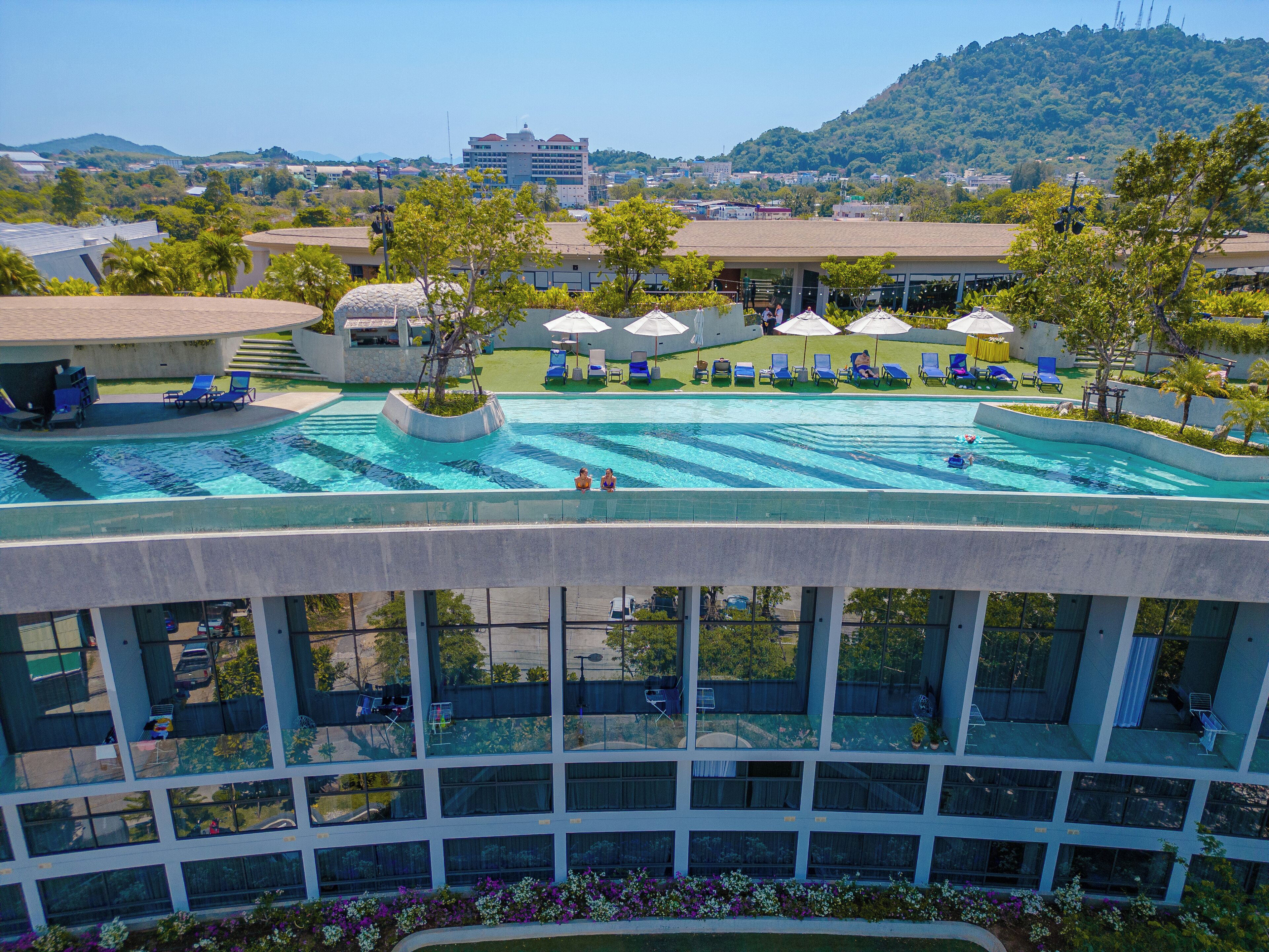A rooftop pool with clear blue water, surrounded by lounge chairs and umbrellas.