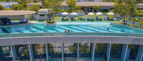 Una piscina en la azotea con agua cristalina y azul, rodeada de sillones de descanso y sombrillas.