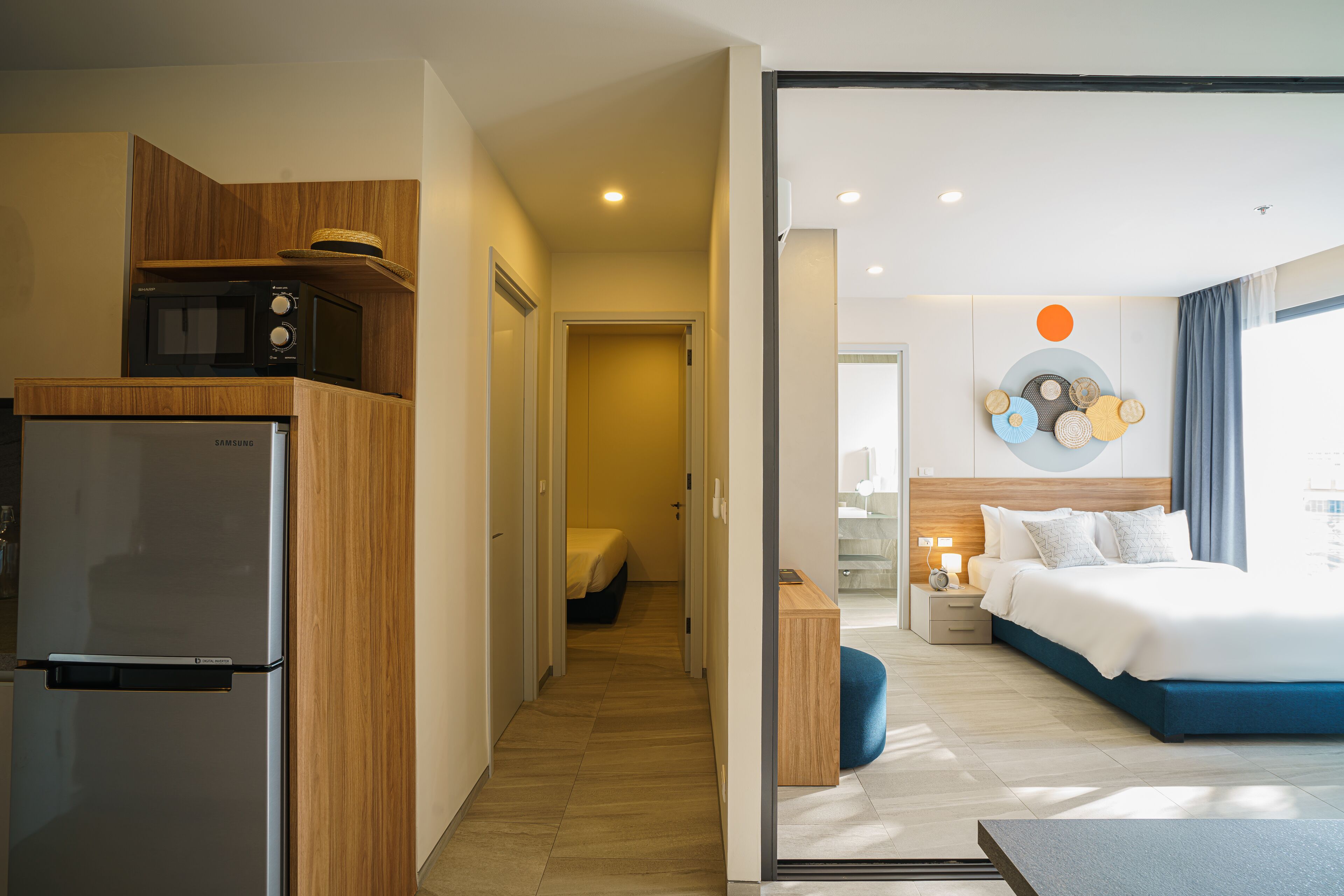 A modern hotel room with a bed, bedside table, and a view of the hallway.