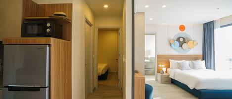 Una habitación de hotel moderna con cama, mesita de noche y vista al pasillo.