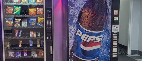 Una máquina expendedora con un anuncio de Pepsi y otra máquina expendedora con productos de snack.