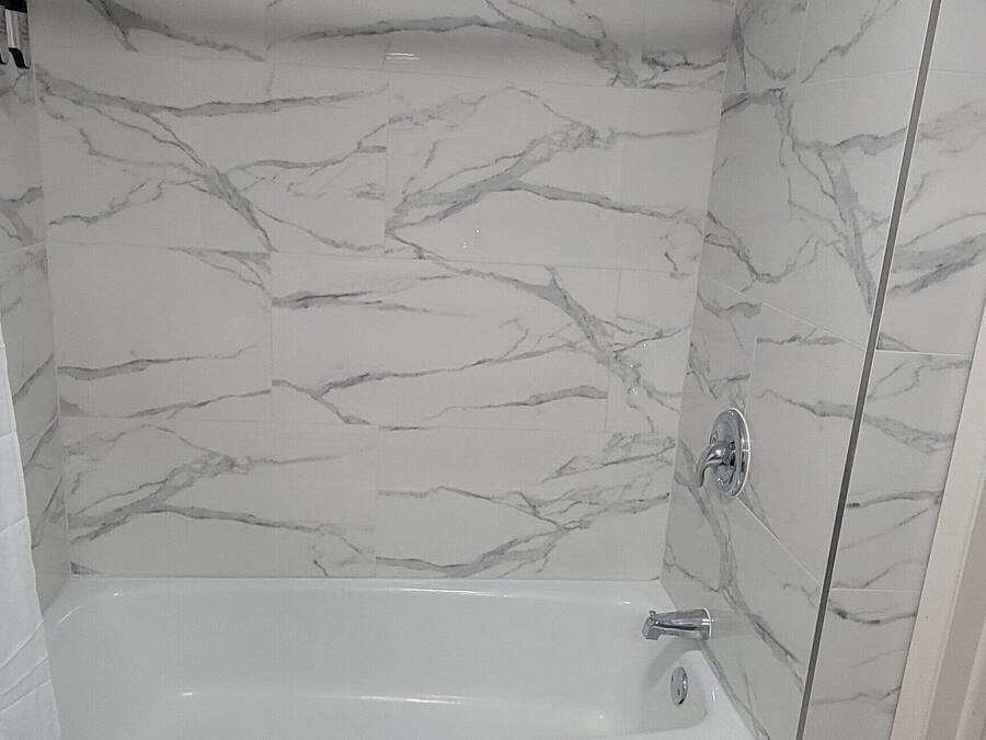 Ein Badezimmer mit Marmorwand, einer Badewanne und einer Toilette.
