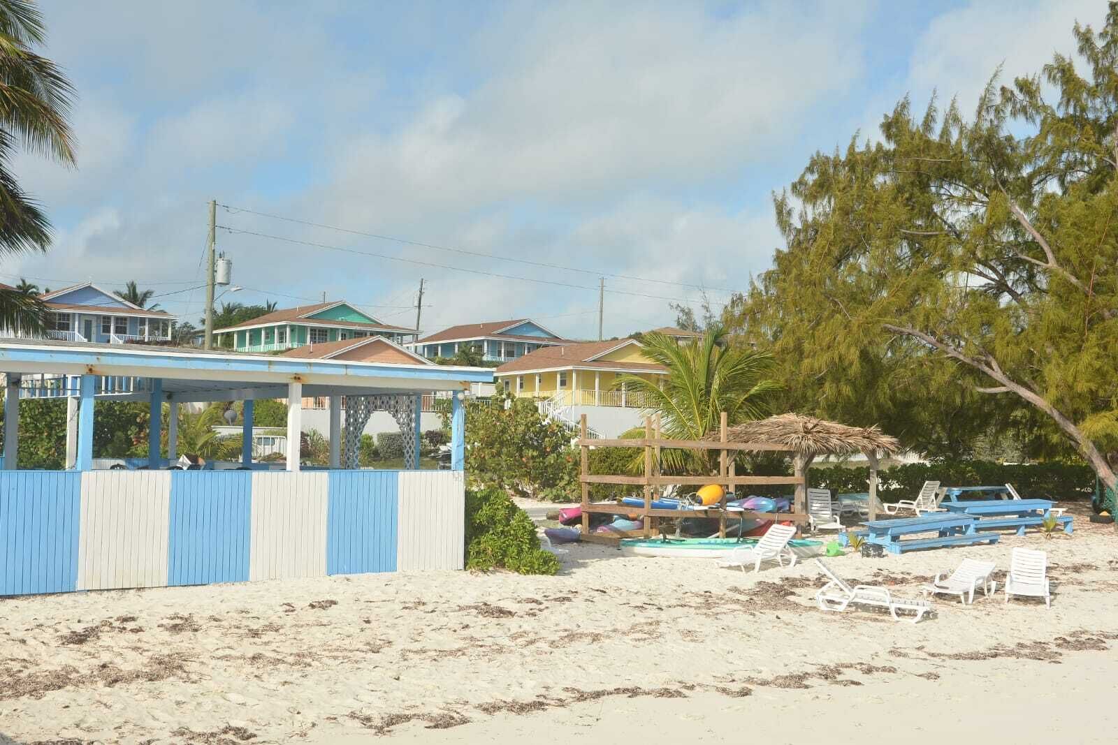 En fastighet vid stranden med ett takförsett område, strandstolar och parasoller.
