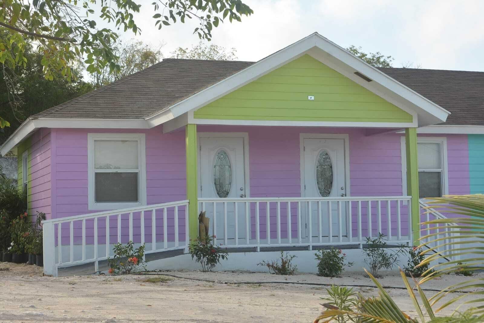 A two-story house with a green front, purple sides, and a white porch railing.