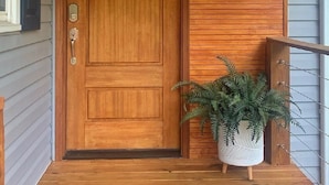 A wooden front door with a glass panel, a small potted plant, and a mailbox on the right side. - Beautiful lake house perfect for amazing getaways! (Fair Play)