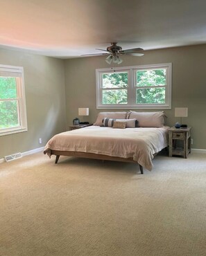 Relax in this serene bedroom with a large bed, two nightstands, and a ceiling fan.