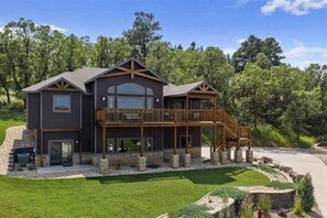 A two-story house with a balcony, a stone foundation, and a landscaped yard. - Spearfish South Dakota rally rental (Spearfish)