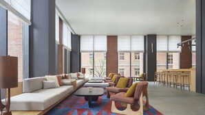 A spacious lounge area with a long sofa, armchairs, and a coffee table. There are large windows providing natural light and a view of the building's exterior. - Hyatt Place Jingdezhen Taoxichuan (Jingdezhen)