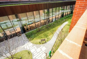 A modern building with large glass windows, a paved courtyard, and a brick wall.