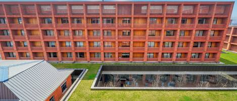 A multi-story building with a grid of balconies, a central courtyard, and a modern glass structure.